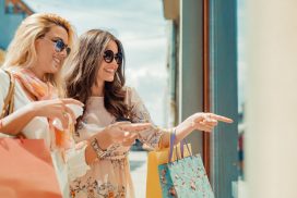 Two women carrying shopping bags and window shopping