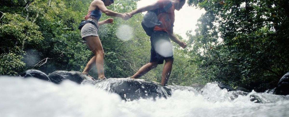 Man and woman hiking across river, low angle view