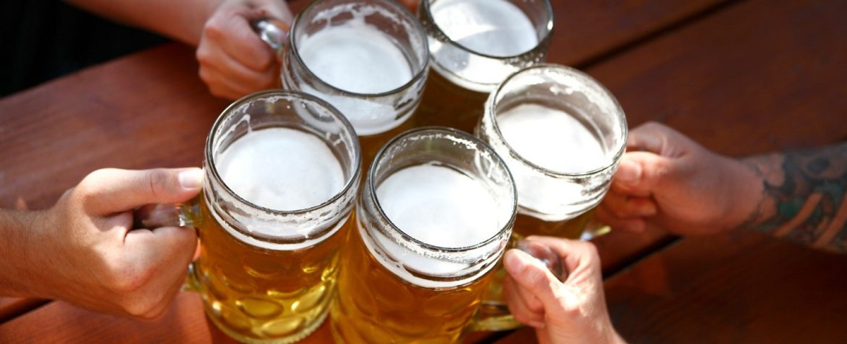 5 friends holding mugs filled with beer to cheers at the Santa Barbara Beer Festival.